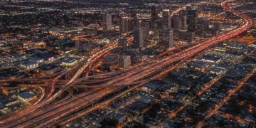 Urban landscape at dusk with illuminated highways, representing US population growth and infrastructure.